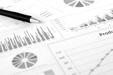 売上や品質データのグラフ資料とボールペンの写真。実務や日常業務でのデータ分析のイメージ